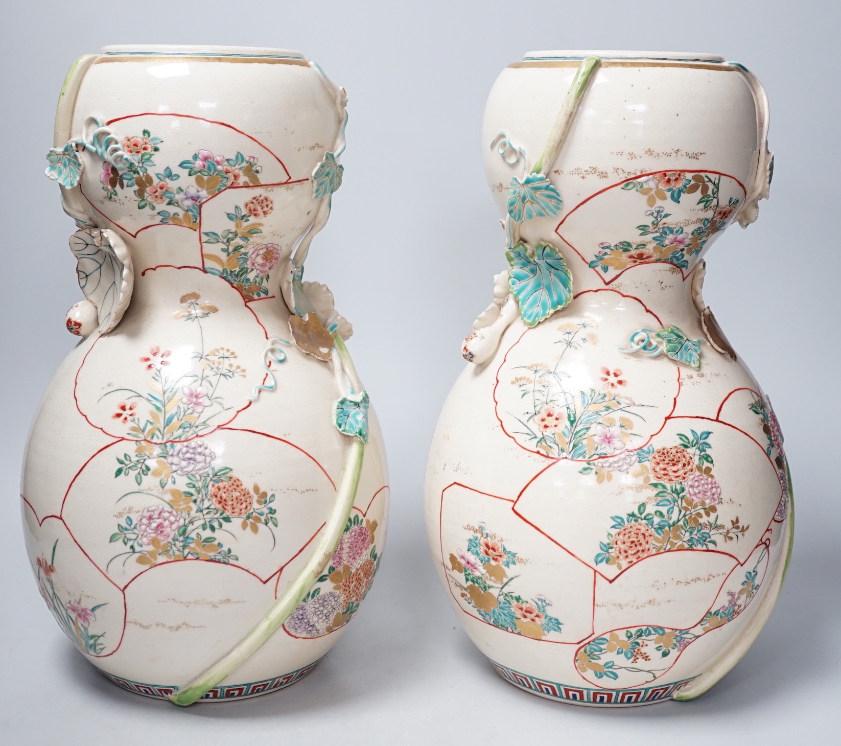 A pair of large late 19th century Satsuma pottery gourd shaped vases, each modelled with a gourd vine, 33cm tall